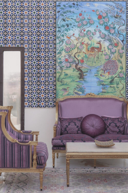 Seating area with purple sofas, decorative cushions, patterned tiles, and wall painting.