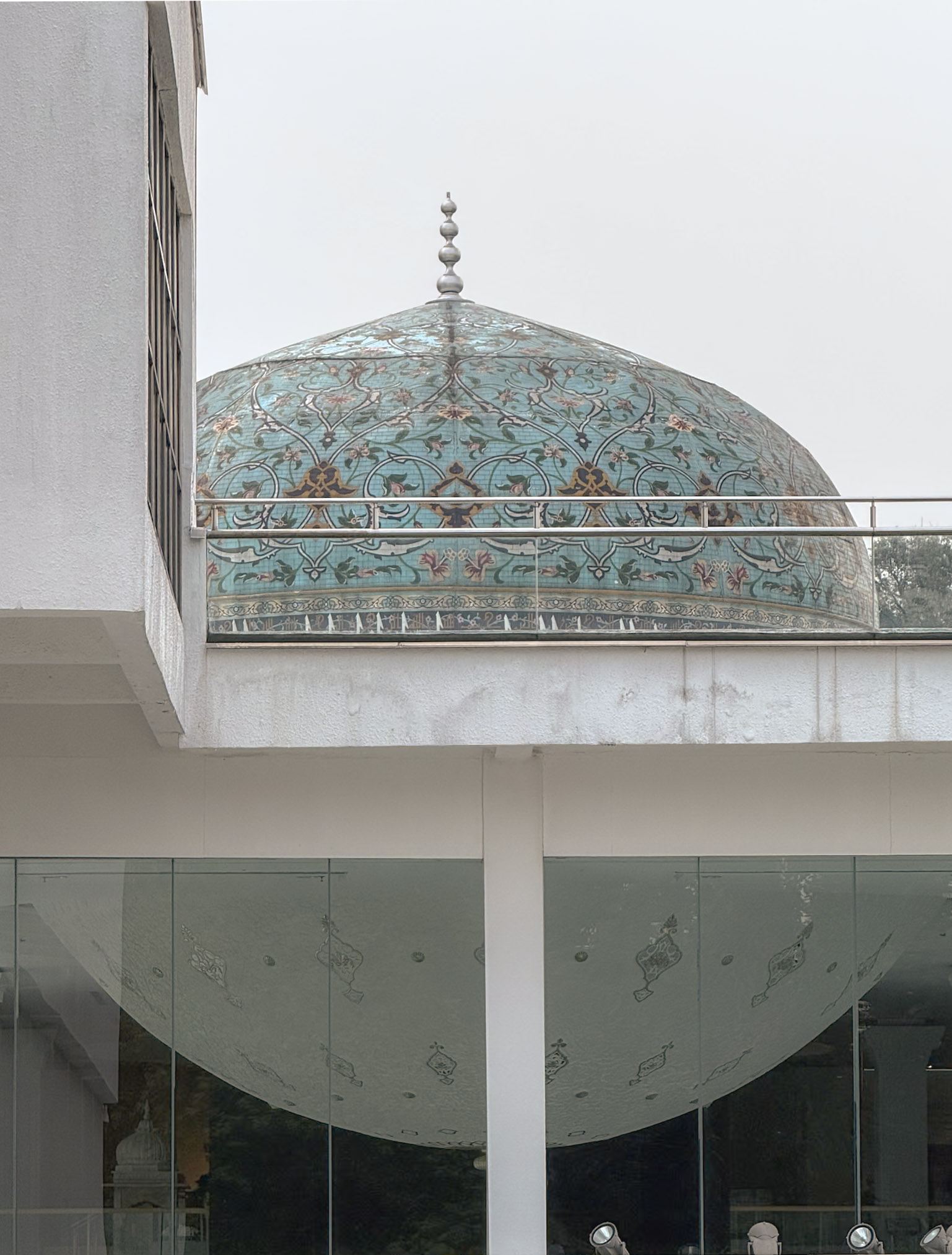 A blue patterned Islamic-style dome seen through modern white architecture and glass at the Islamic Arts Museum in Kuala Lumpur.